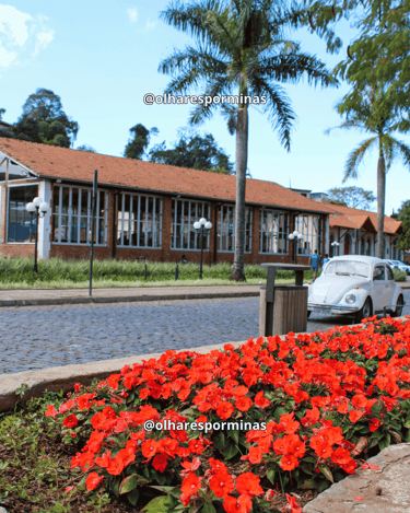 Antiga estação ferroviária de Itabirito MG com jardim florido, palmeiras e fusca branco