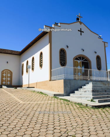 Vista lateral da Igreja de São Pedro em Cristiano Otoni, com calçamento de pedra e céu aberto