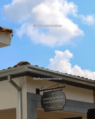 Placa da Casa das Tecelãs em Brumal Minas Gerais com céu azul e arquitetura colonial
