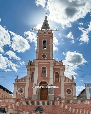 Vista frontal da Igreja Matriz de Dores do Campo MG sob céu azul com nuvens