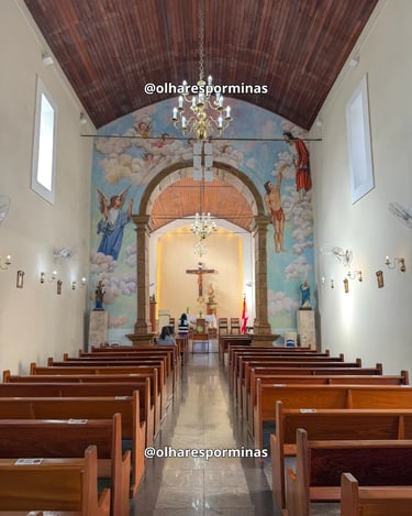 Interior da Igreja Matriz de Itatiaiuçu com bancos de madeira, lustres e pinturas religiosas no alta