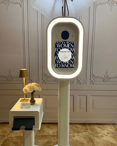 Modern white DSLR photo booth for events with a touch screen display and printer.