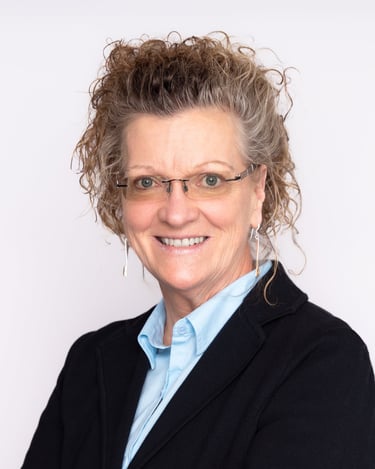 a woman with glasses and a blue shirt smiling