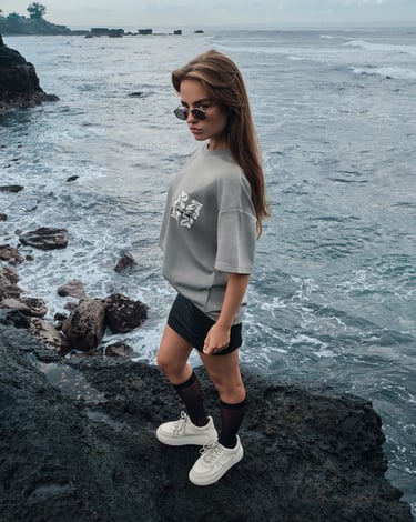 Model in an oversized shirt and mini skirt poses in a preppy street style on Bali’s volcanic coast.