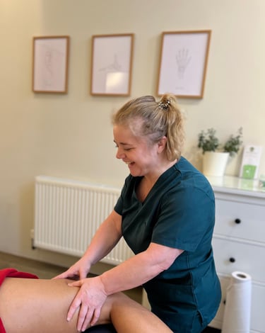 female massage therapist delivering sports massage to patient in clinic