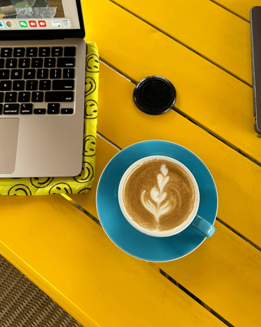 a laptop computer and a cup of coffee on a yellow table