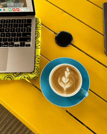 a laptop computer and a cup of coffee on a yellow table