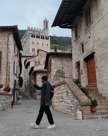 Traveler walking through medieval Gubbio streets near Palazzo dei Consoli on a guided tour in Umbria