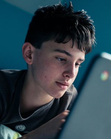Teenage boy using laptop unsupervised, illustrating risks of online activity