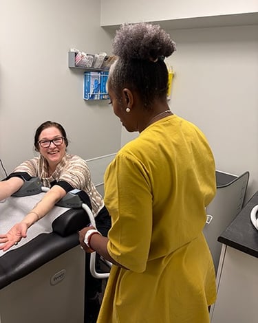 A patient in a doctors office using the BLT  Emsculpt on her arms talking to dr. aluko