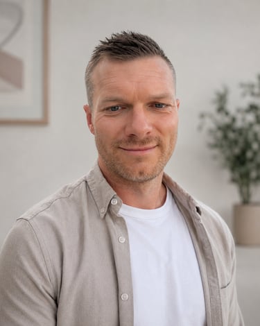 Professional headshot of a smiling man with short hair wearing a beige button-down shirt.