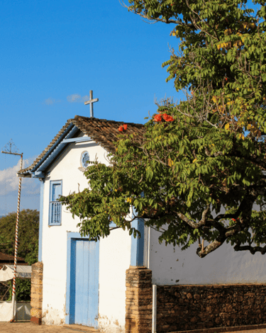 Capela do Senhor do Bonfim com uma árvore em frente em Morro D'Água Quente MG