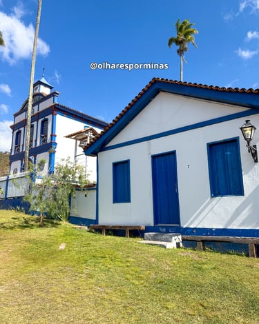 Casa com dores azul e branco com uma igreja ao fundo na Vila do Biribiri em Diamantina MG
