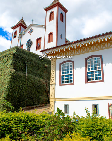 Igreja do fundo com uma casa em estilo colonial na frente em Serro MG