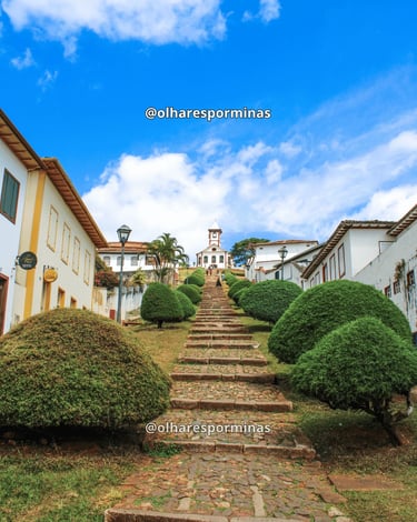 Escadão de pedra cercado por casarões e jardins conduz à Igreja de Santa Rita, no Serro