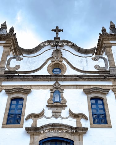 Detalhes da fachada barroca da igreja de Glaura MG com janelas azuis e cruz
