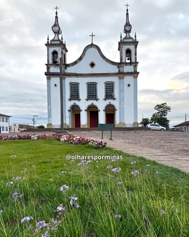 Igreja Matriz de Catas Altas com o jardim florido da praca em frente