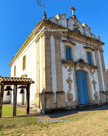 Igreja Matriz de Lobo Leite com fachada histórica, porta azul e sino lateral em Minas Gerais