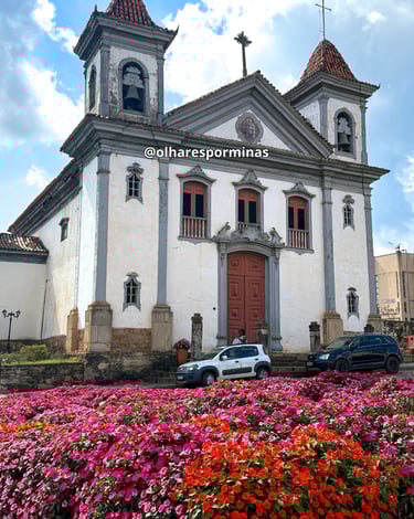Igreja Matriz de Santa Bárbara com um jardim florido em frente, ponto turistico em Minas Gerais