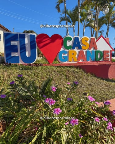 Letreiro turístico de Casa Grande, em Minas Gerais, com flores e palmeiras ao redor