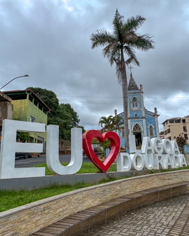 Letreiro eu amo Lagoa Dourada com igreja e céu nublado no fundo