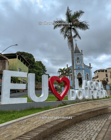 Letreiro Eu Amo Lagoa Dourada com igreja azul ao fundo no centro da cidade em Minas Gerais