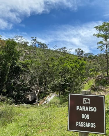 Placa do Paraíso dos Pássaros na Serra da Canastra MG, com paisagem natural e cachoeira ao fundo