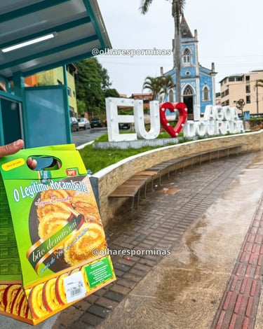 Rocambole tradicional de Lagoa Dourada com letreiro turístico e igreja ao fundo em Minas Gerais