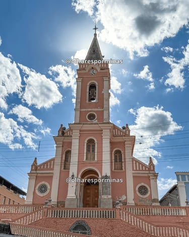 Vista frontal da Igreja Matriz de Dores do Campo MG sob céu azul com nuvens