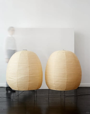 Two warm Akari paper lamps with rounded shapes, creating gentle diffused light in a calm modern inte