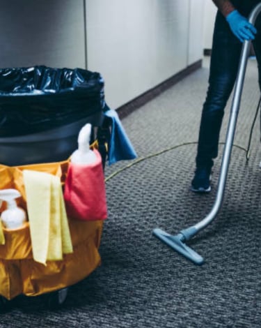 Vacuuming carpet near trashcan