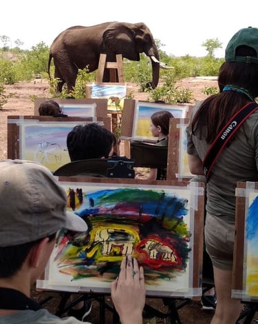 a group of people are painting an elephant on a field