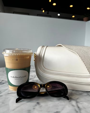 a white purse with sunglasses and a coffee cup