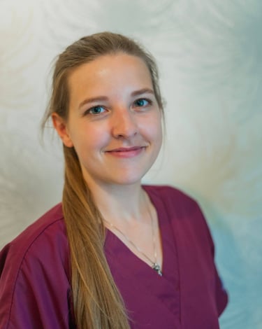 Profile of a young woman with dark brown hair wearing burgundy scrubs