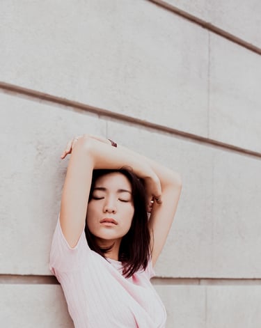 portrait de femme les mains au dessus de la tête adossée contre un mur