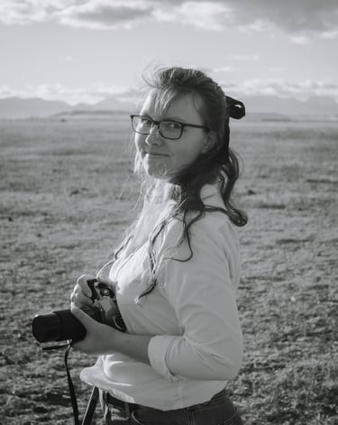 a woman in glasses and a white shirt is holding a camera