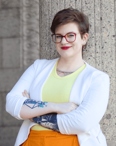 a photo of Swana Schuchmann with short hair, a white blazer and glasses, smiling