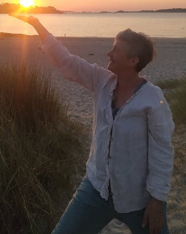 a woman is standing on a beach with her arms outstretched out to the sun