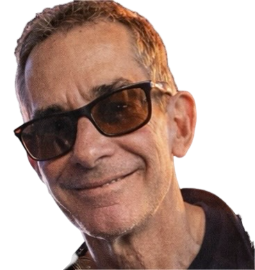 Tom wearing dark-rimmed glasses against a black background.