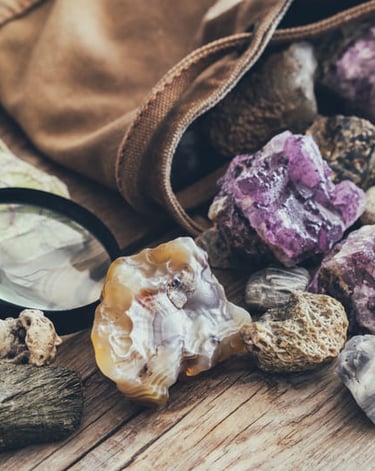 Colección de cristales de amatista en bruto y especímenes minerales geológicos con lupa sobre madera