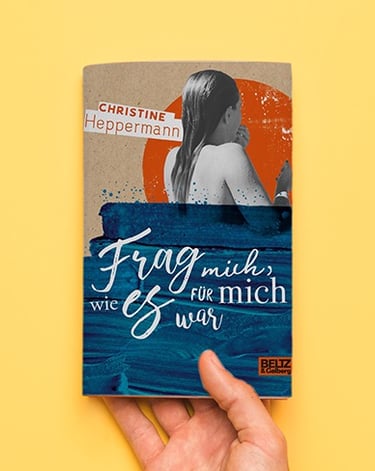 Eine Hand auf gelben Untergrund hält das Buch "Frag mich, wie es für mich war."