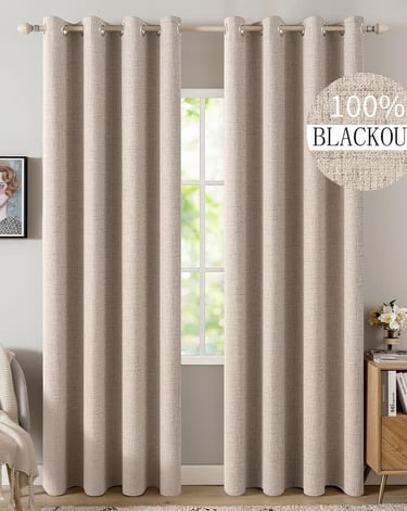 Beige 100% blackout curtains with grommets hanging on a wooden rod over a living room window.
