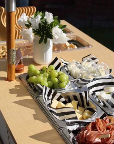 top of a bar cart with charcuterie items in containers and flowers