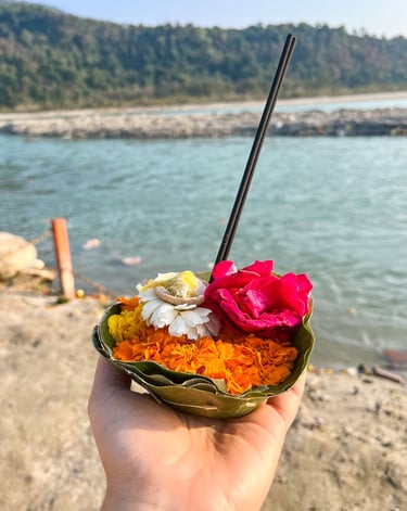 Close-up of flowers and incense sticks arranged as an offering during a ritual by the Ganges River.