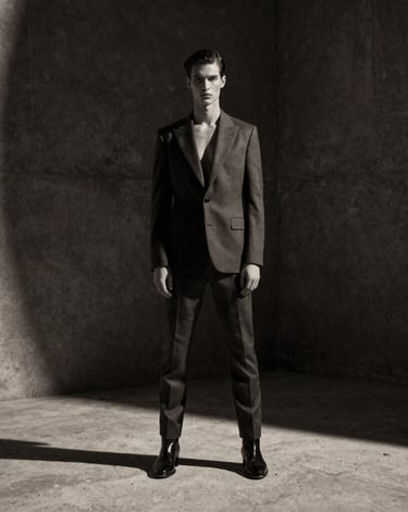 Cinematic wide shot of a high-fashion editorial model on a dramatic concrete set in Dubai, high-contrast studio lighting, deep shadows, anamorphic lens, 35mm monochrome