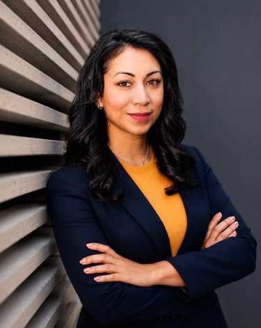 Professional corporate headshot of a business woman in a navy blazer against a modern backdrop.