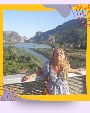 Martina smiling standing on a bridge in the mountains.
