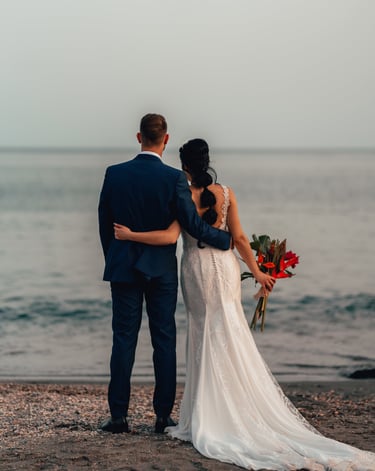 una novia y un novio en una playa abrazándose en el día de su boda