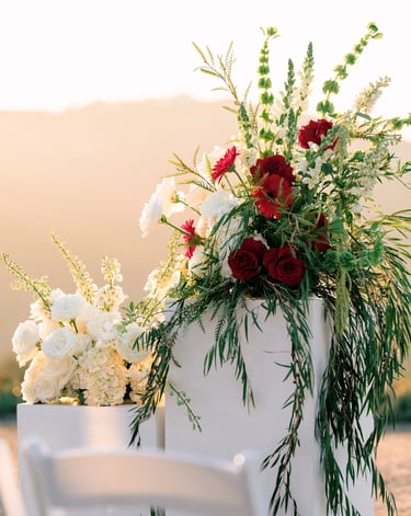 red and white wedding arrangements on white pedestals