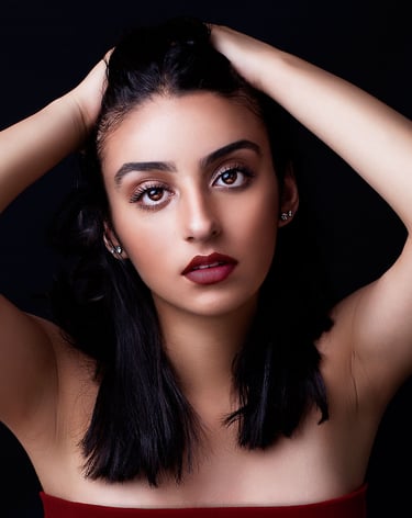 a beautiful brown eyed girl with tanned skin, plump auburn lips, pulling her hair back and posing like a model